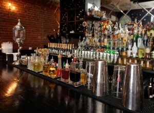 Bitters and infusions on bar counter with blurred bottles in bac